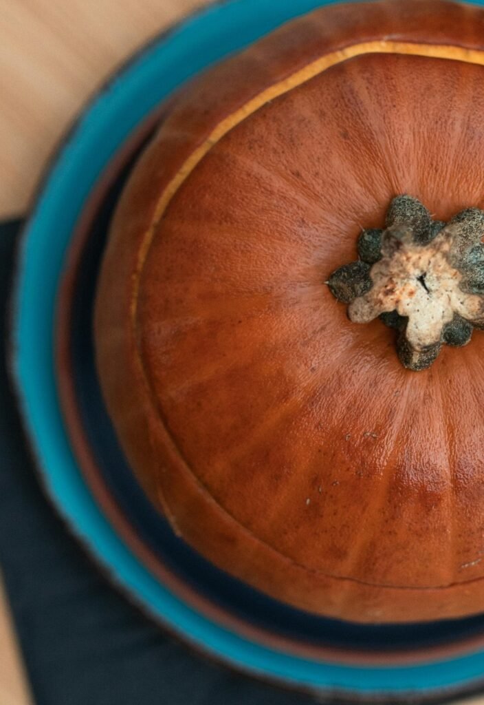 Overhead shot of a pumpkin placed on a rustic blue plate, showcasing autumn vibes.